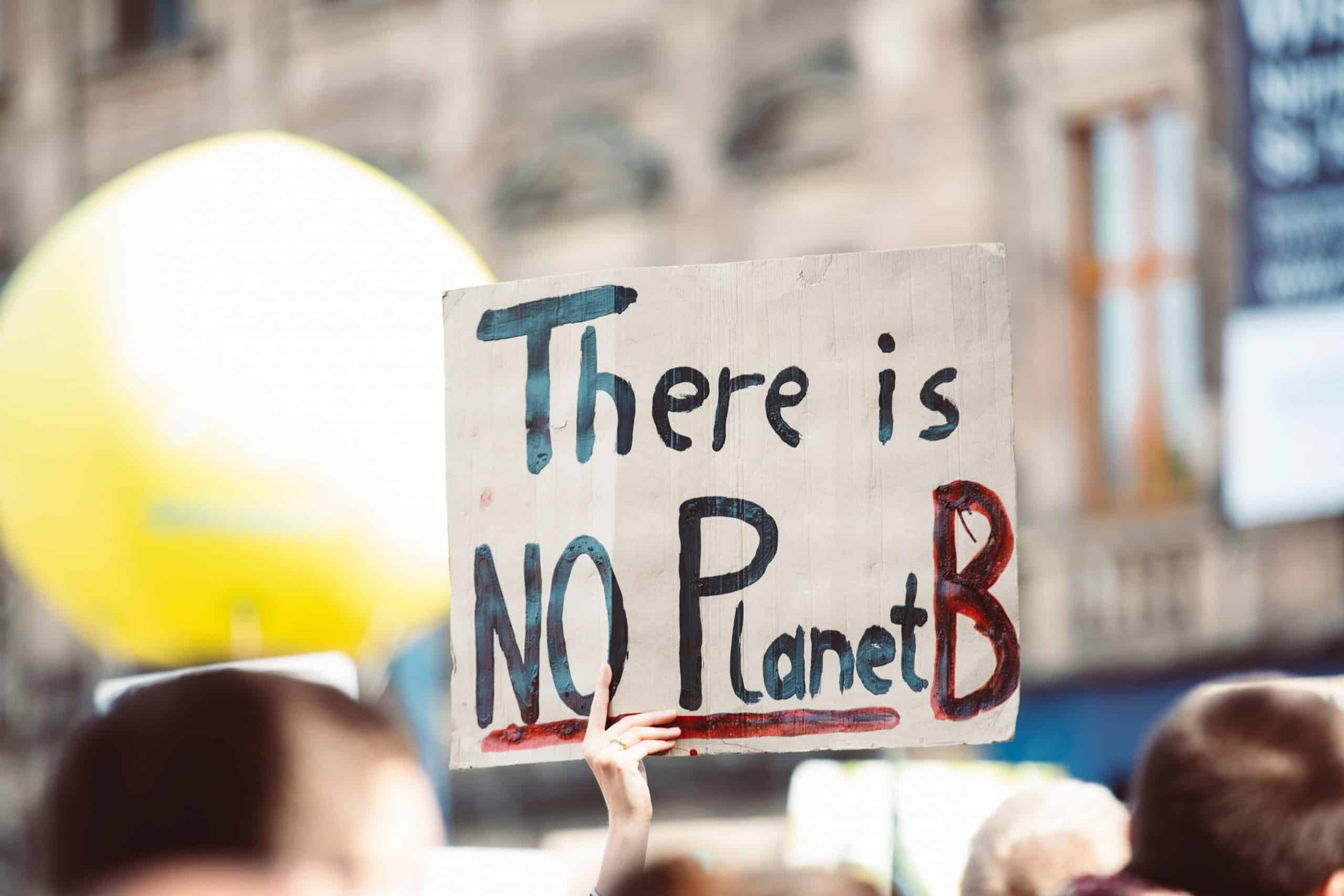 Man houdt een bord omhoog met de titel "Er is geen planeet B".
