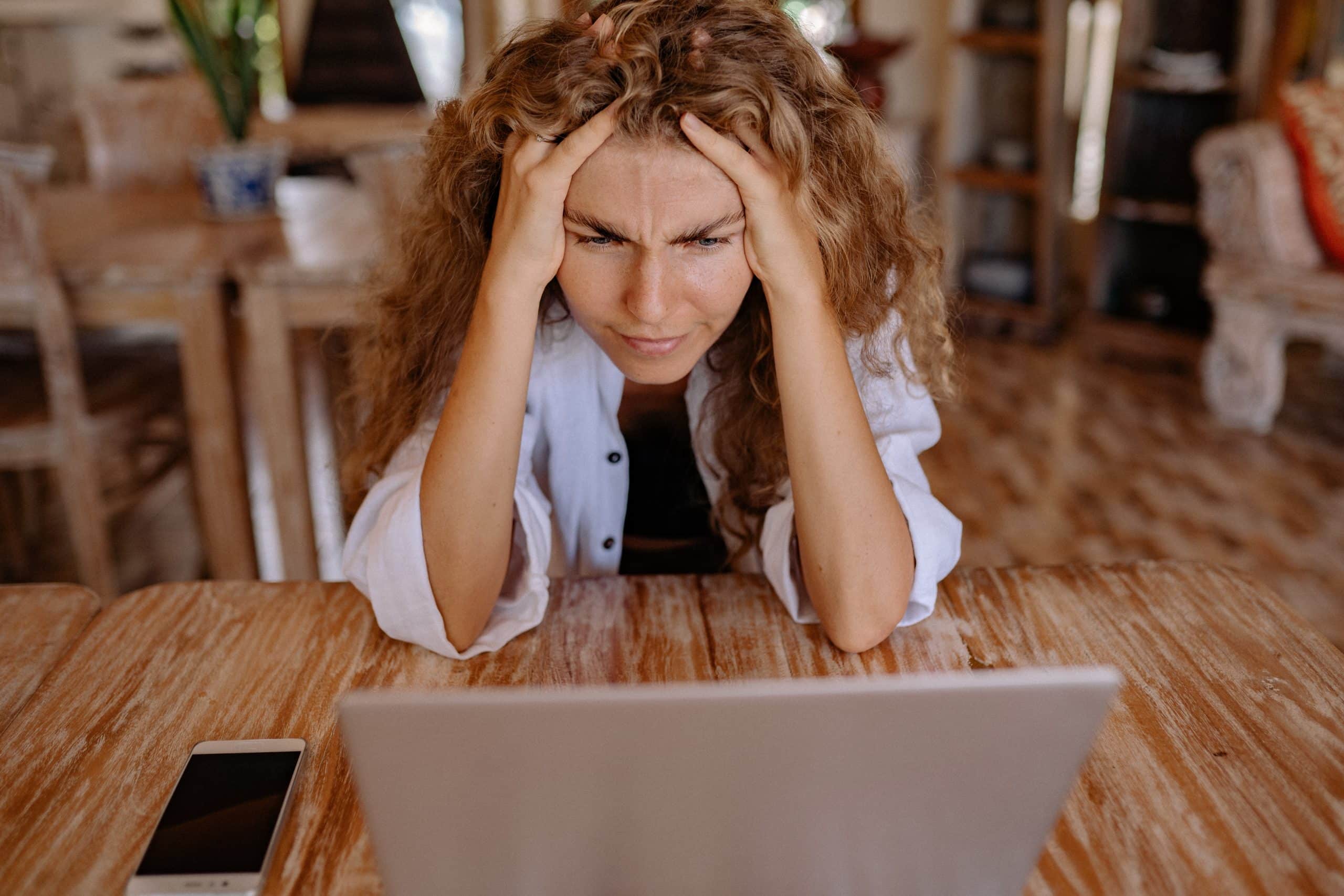 Woman sits in front of laptop and has a headache. Your health is important.